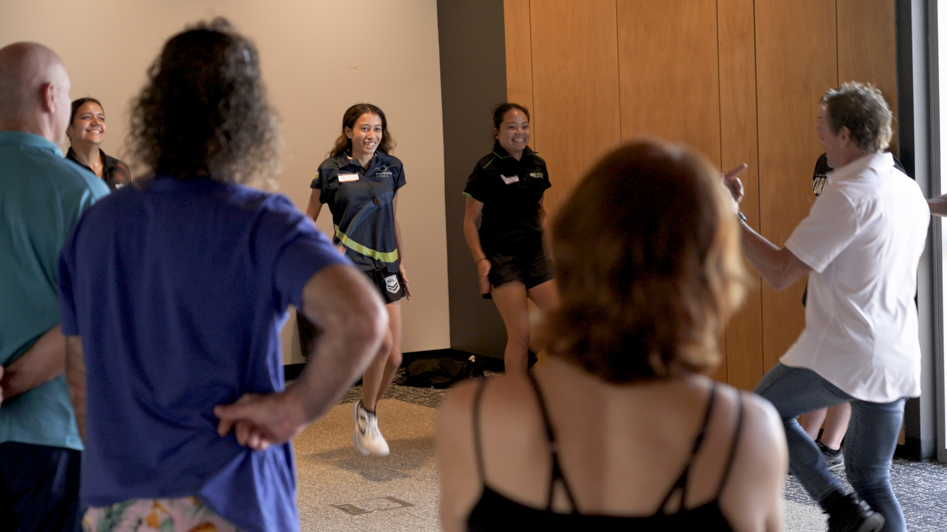 People stand in a circle participating in a workshop on physical literacy.