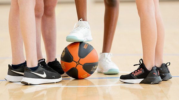 Close up of basketball players legs with one foot on a basketball.
