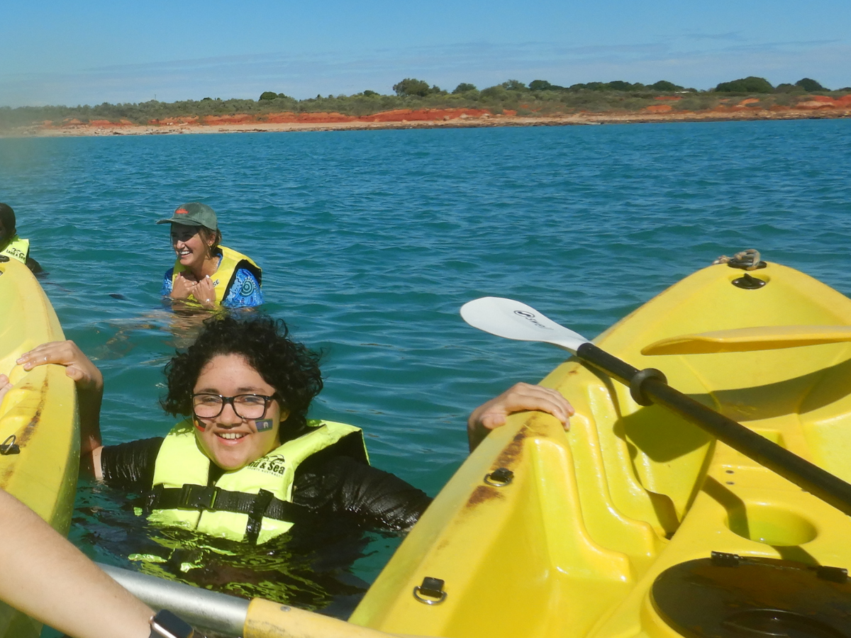 A student is in the water between two kayaks