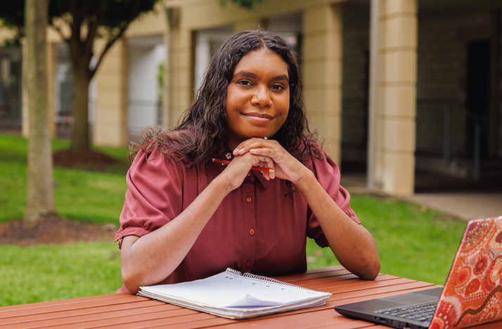 First Nations woman sitting at an outside table with her computer