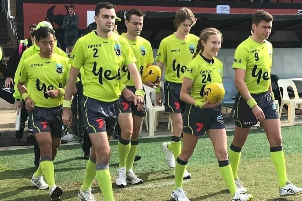 AFLW umpire Courtney Gibson walking out onto the field with fellow officials