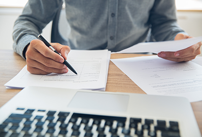 Man sitting at a desk holding a pen in one hand and a document in the other