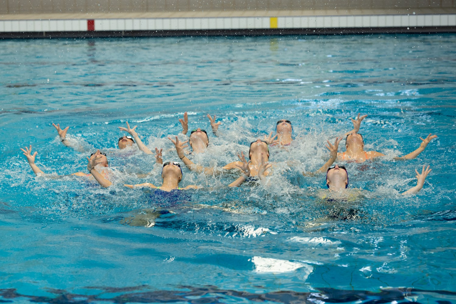 A group of artistic swimmers in a pose above the water