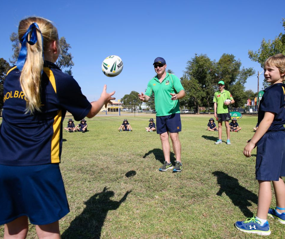 Students playing rugby with their PE teacher at school