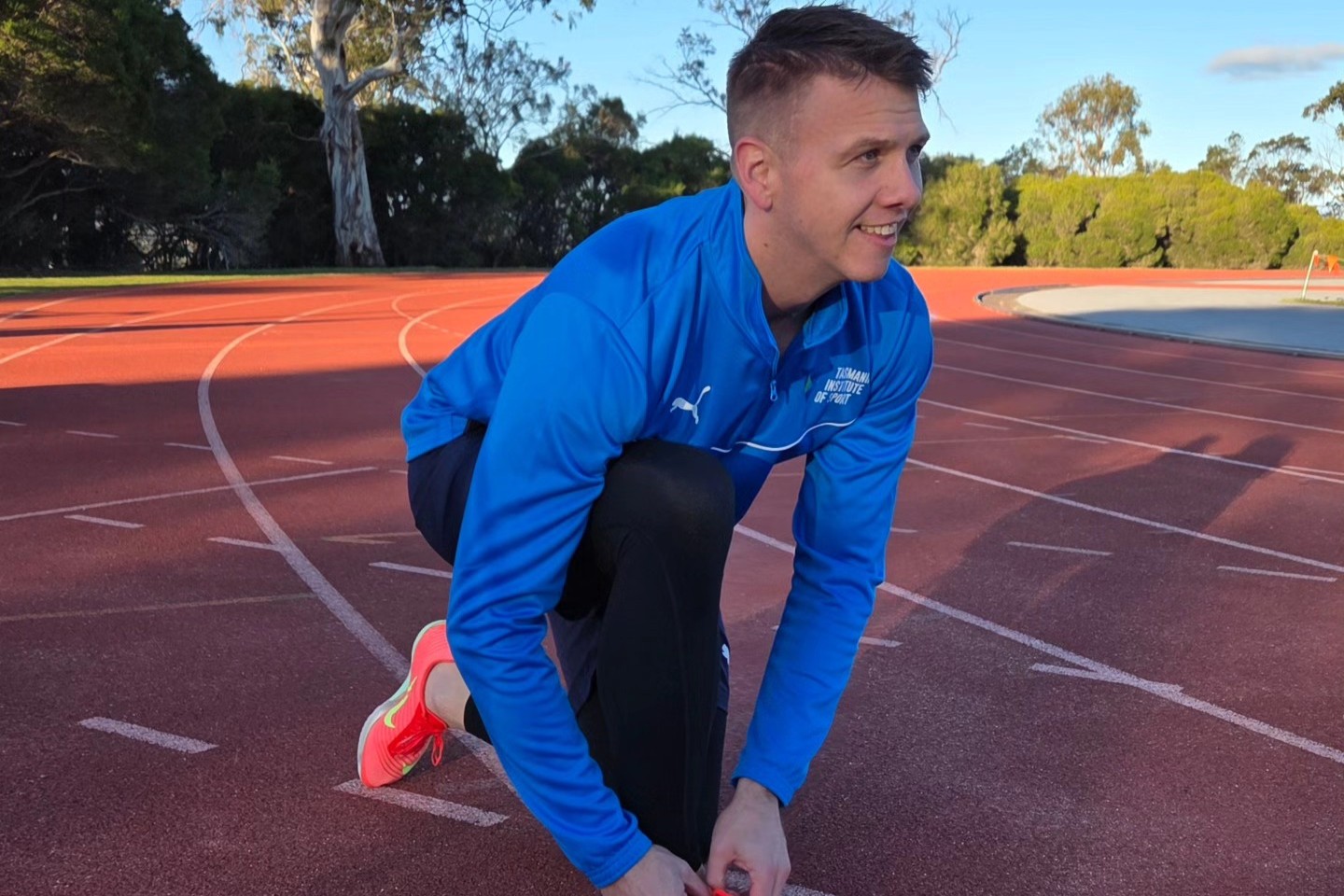 Sprinter Shannon Winchester ties up his spikes on an athletics track