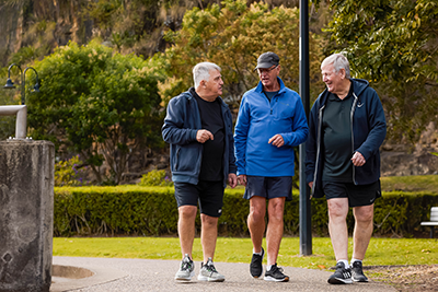 Three mature aged men taking a walk outside.