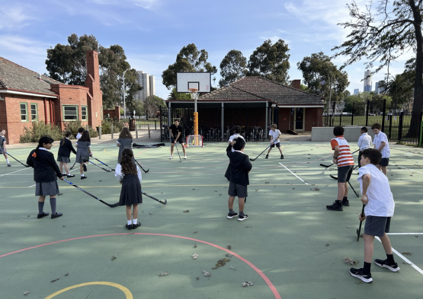 Group of students playing street hockey with a coach