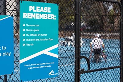 Court side signage asking parents, friends and coaches not to get involved and let the kids play Tennis.