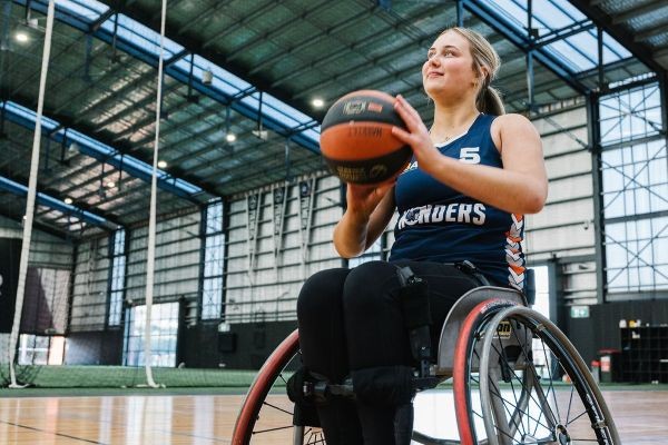 Young lady about to pass a basketball from a wheelchair