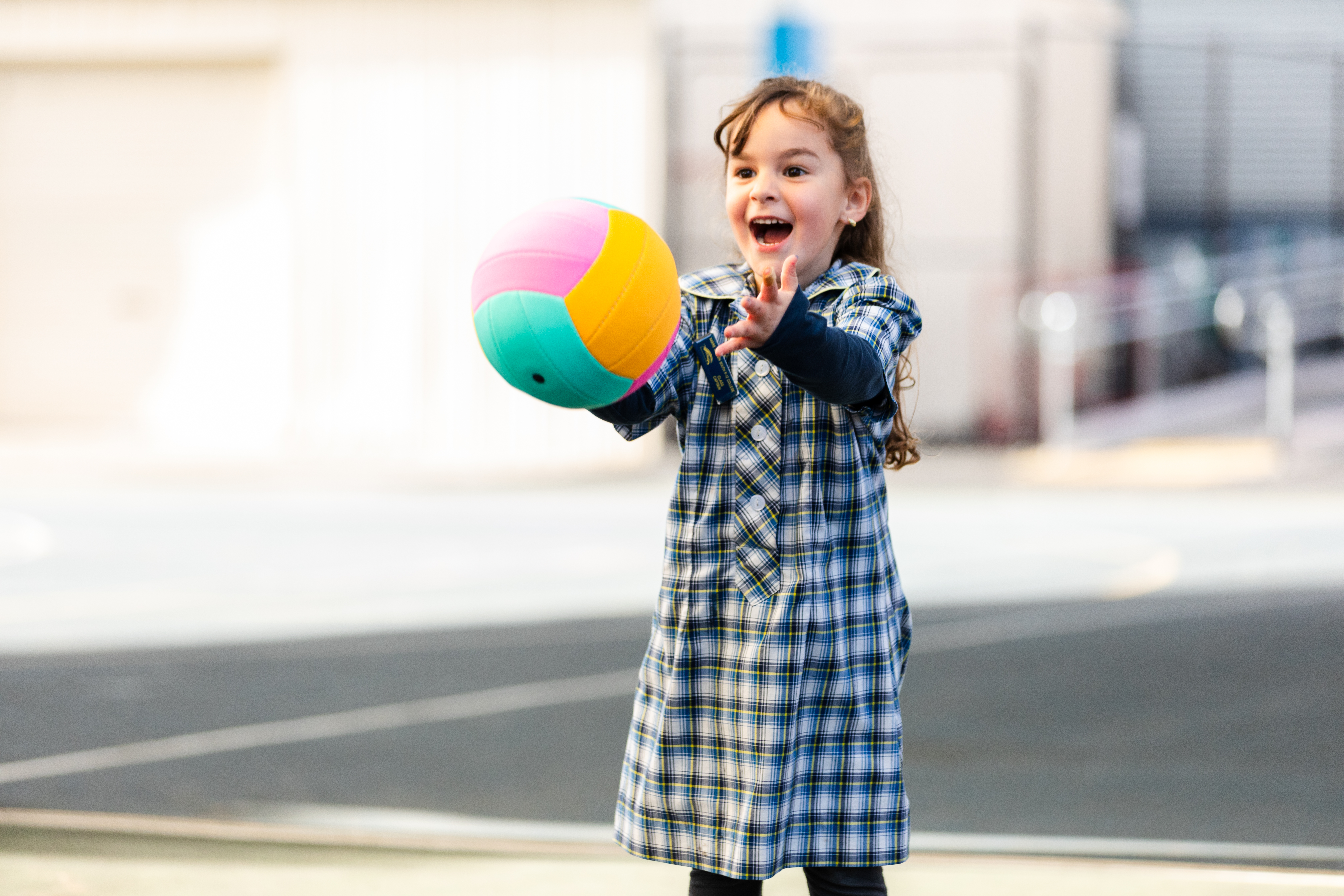School girl throwing a netball with an excited face