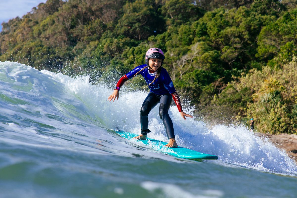 Teenager learning to surf a small wave and smiling