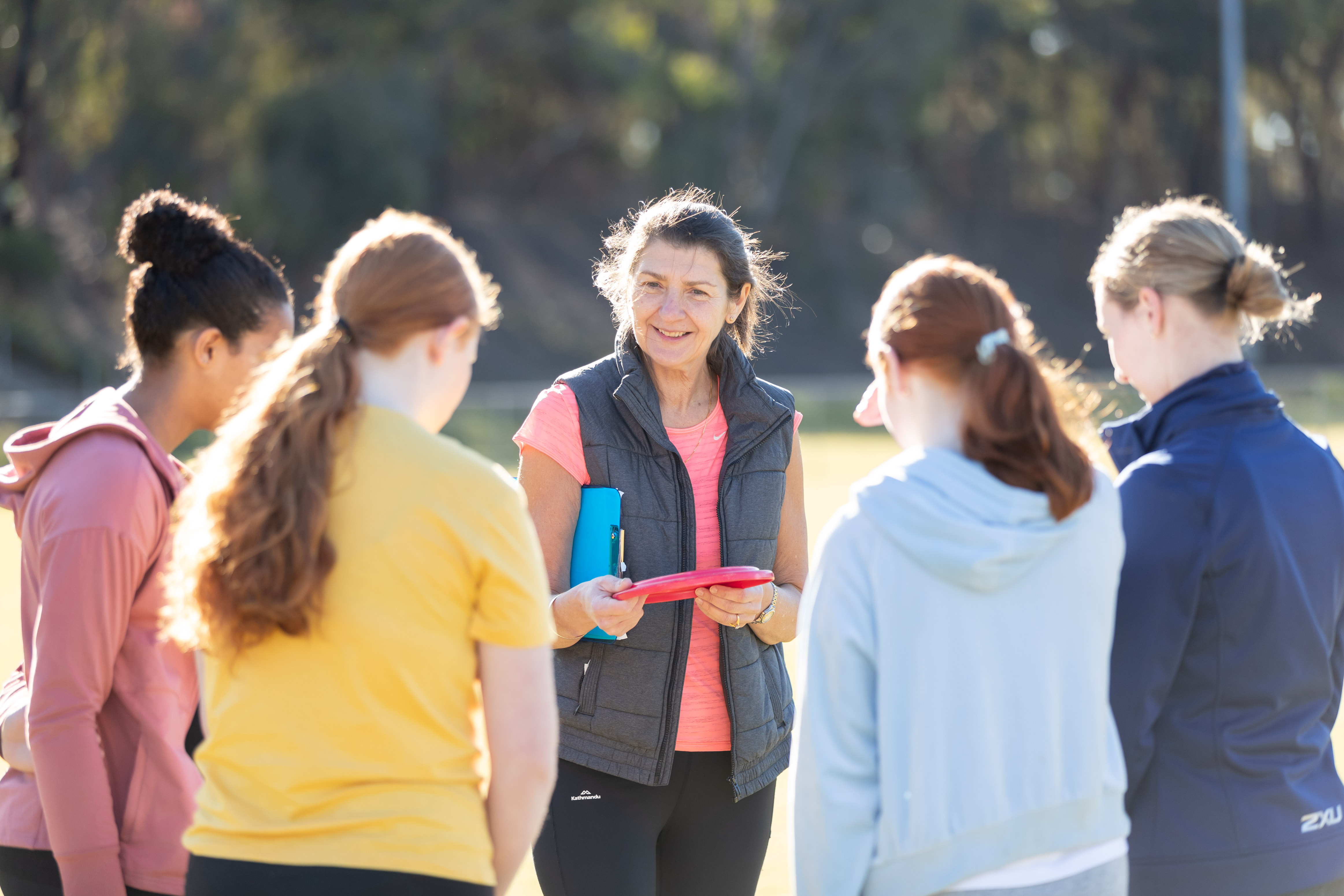 A coach stands with four community players before a social game