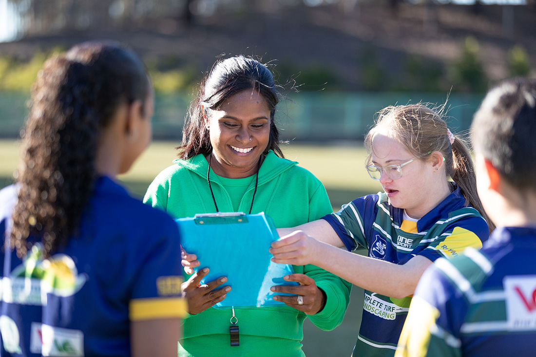 Volunteer coach with junior athletes looking at a clipboard