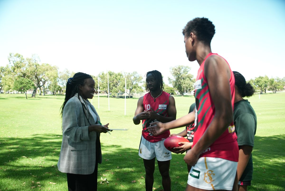 Woman official with young men playing AFL at a park