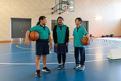 Three children of different ethnicities and backgrounds, each holding a basketball