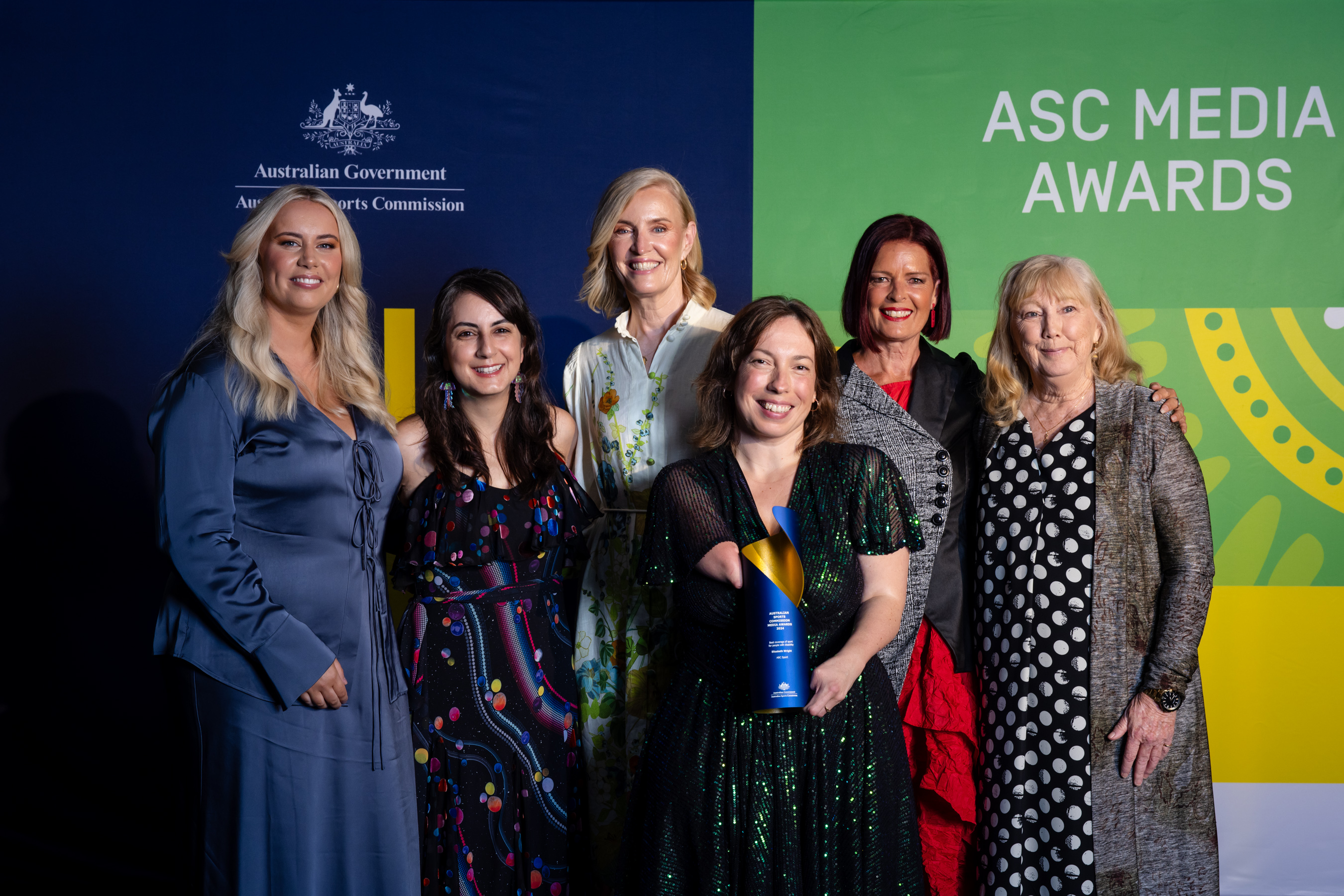Image of Elizabeth Wright holding her trophy surrounded by former and current ABC colleagues at the ASC Media Awards