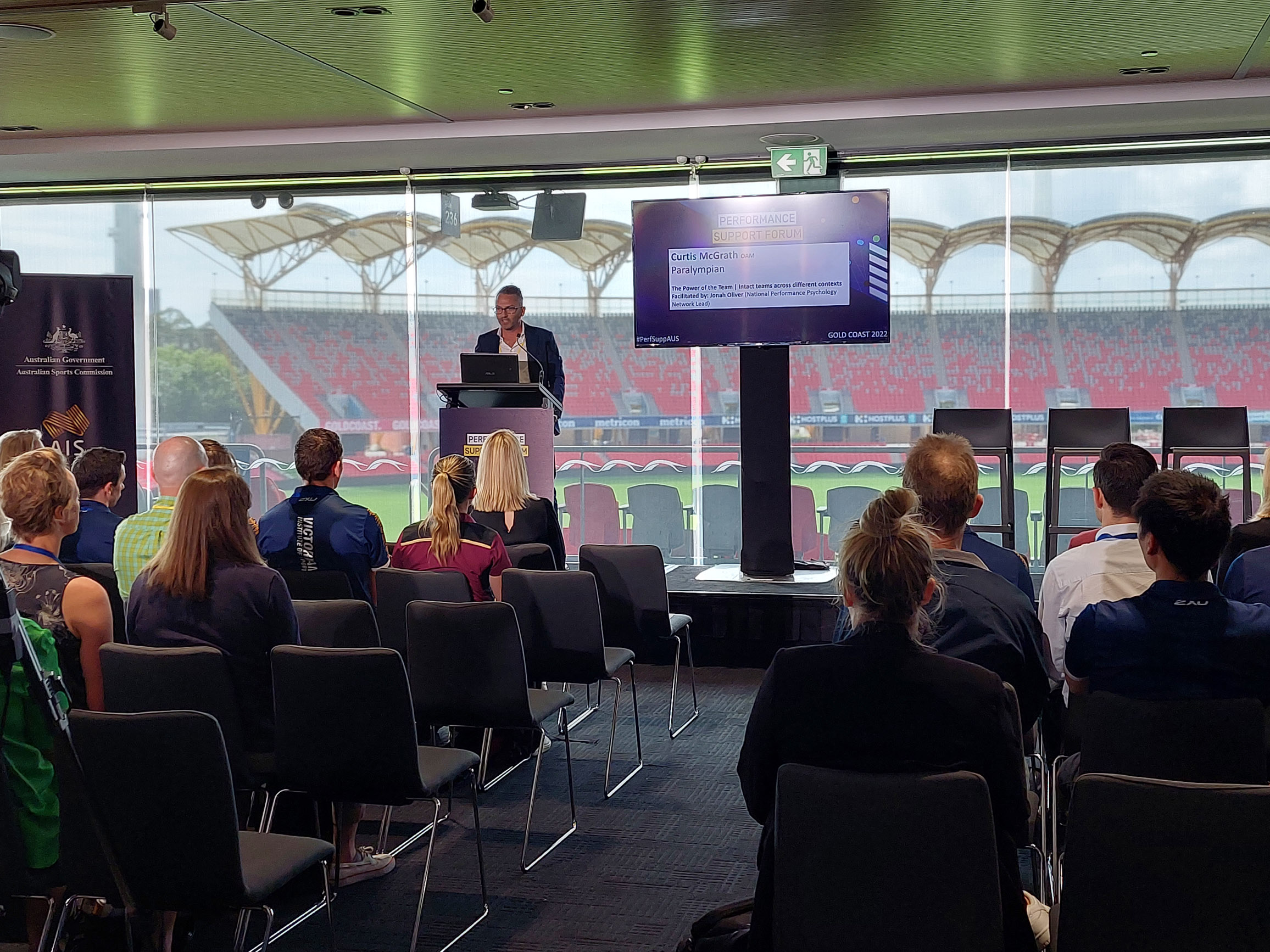 A crowd of people at a conference with the presenter talking