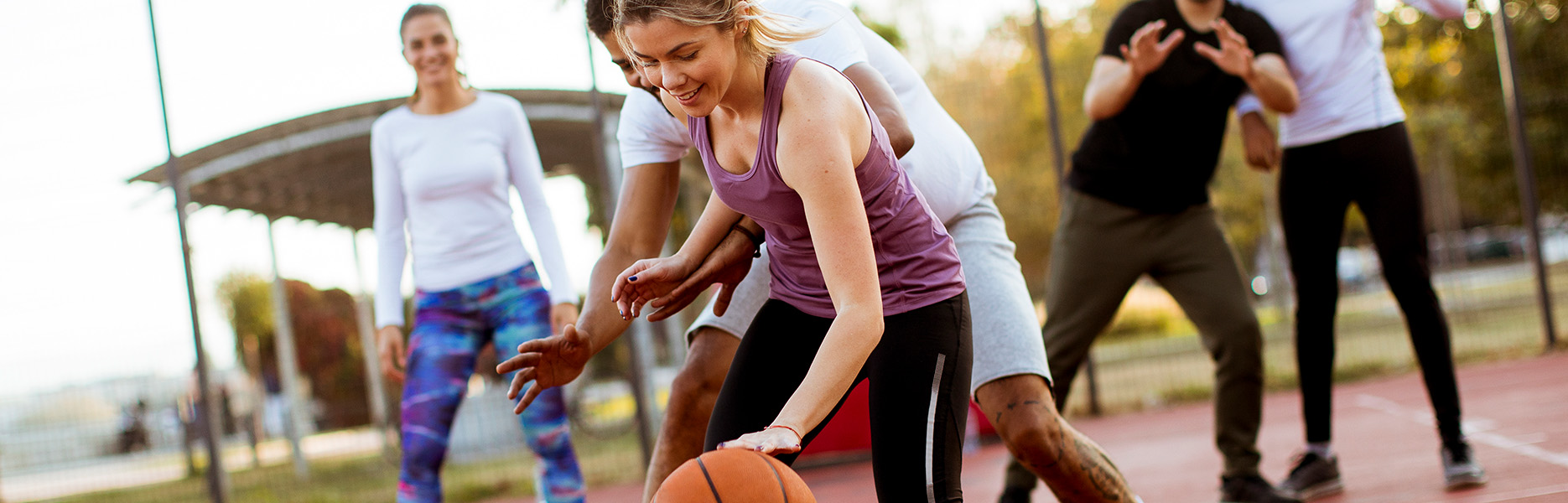 Group of young people playing basketball outdoors