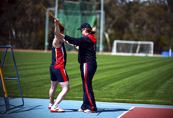 Athletics coach working with an athlete who is holding a javelin